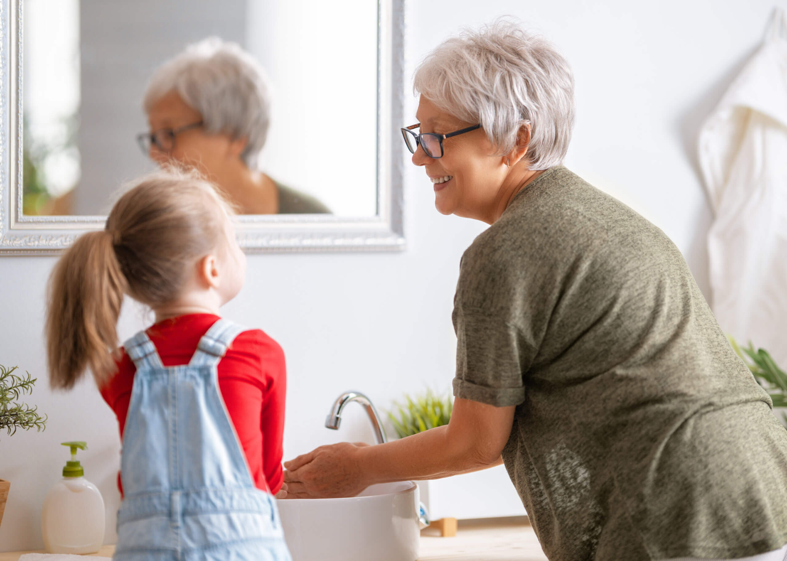 girl and her grandmother are washing hands